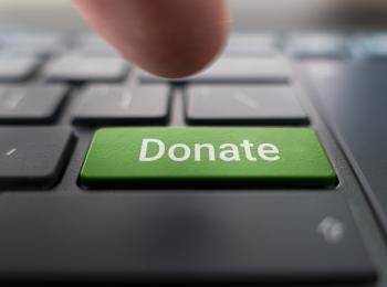 Half of an index figure pointing to a green donate button on a keyboard
