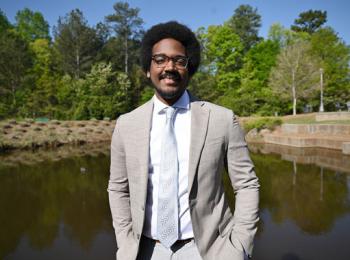 Nolbert Sanchez standing in front of a pond smiling at camera