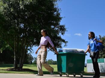 Two students moving a cart with personal items