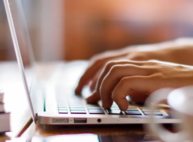 hand with gold watch typing on laptop