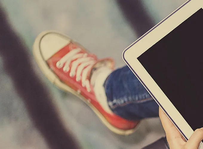 student with tablet and red sneakers