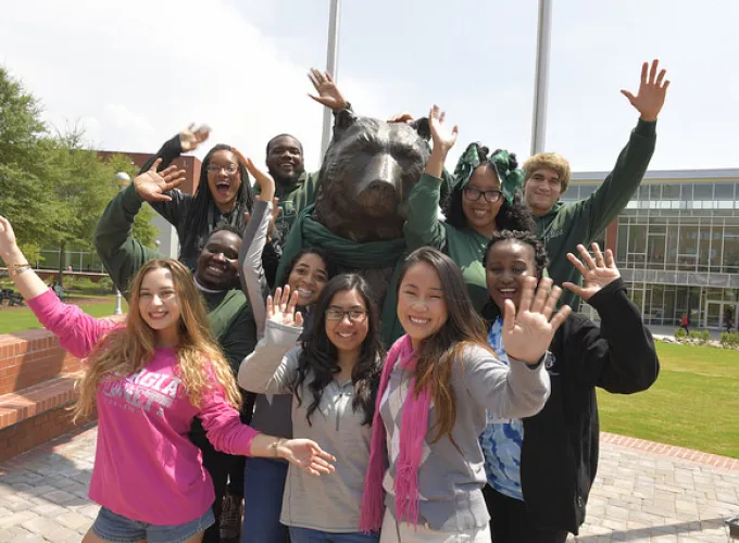 GGC students waving and surrounding Grizzly statue