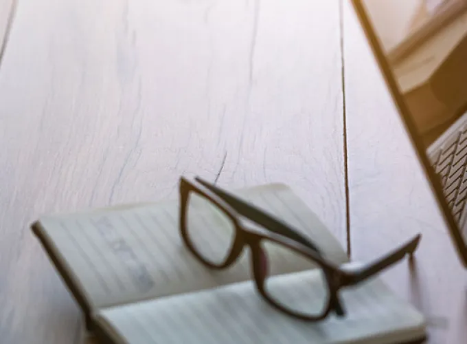 student typing on laptop next to eyeglasses