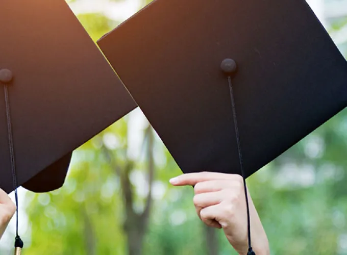 Four graduates holding up their commencement caps