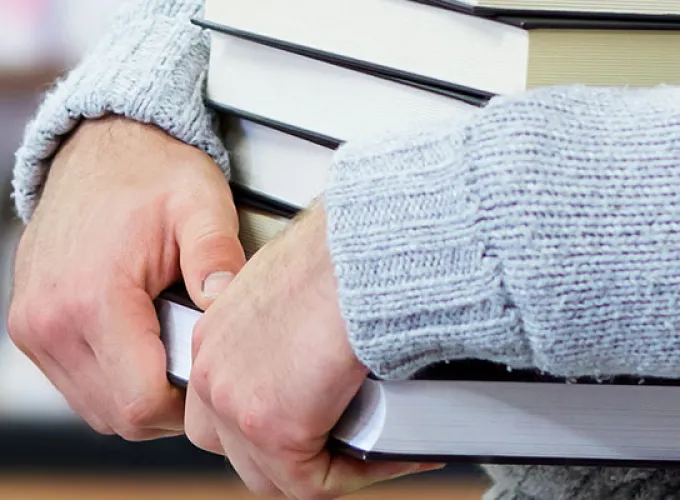 person in sweater carrying books