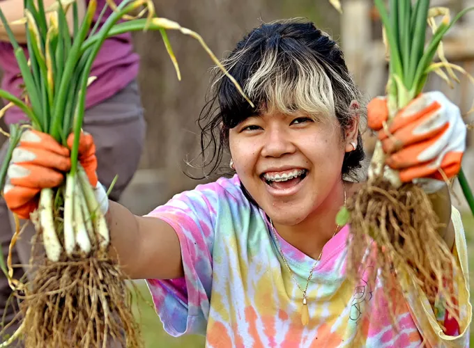 GGC campus microfarm student volunteer holding up green onions