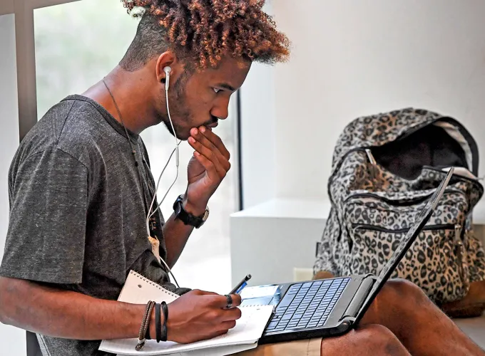 Student studying with notebook and laptop