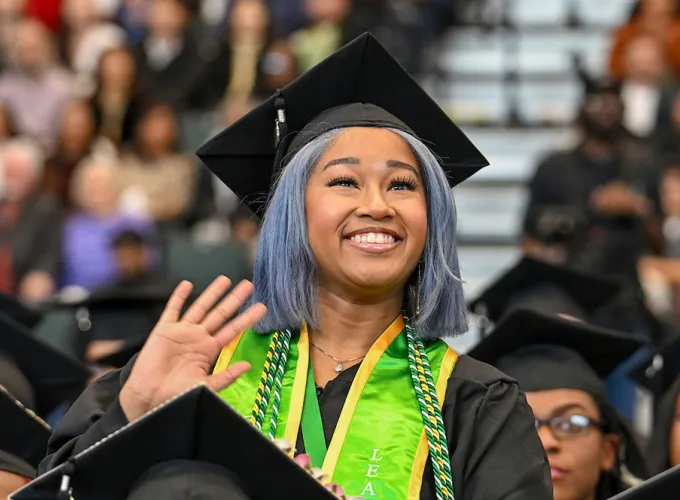 female GGC grad waving to family