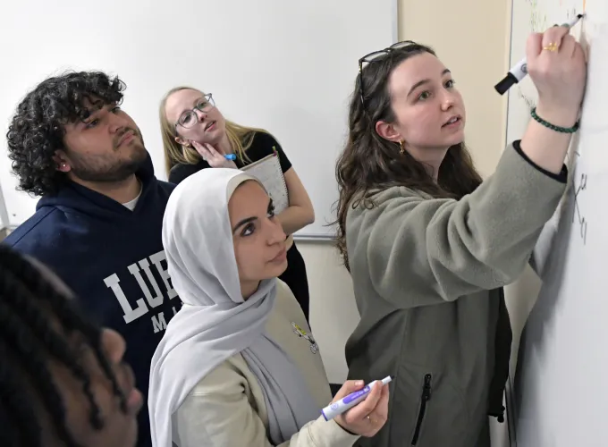 Students watching another student write on the classroom board