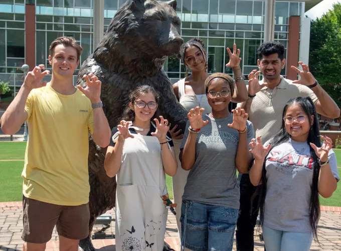 Group of students surrounding the Grizzly statue