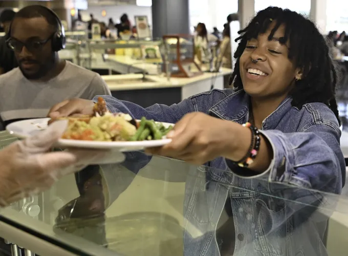 female student receiving plate from dining worker