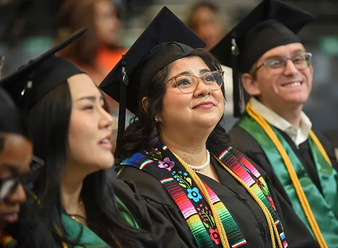GGC graduates seated in audience and wearing honor cords
