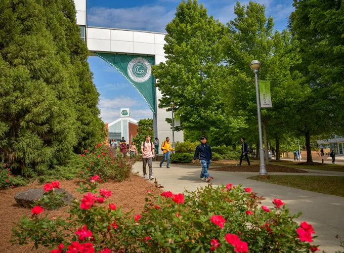 Students walking under the Arch of Knowledge with Building B in the background