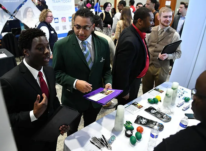 Professionally dressed students talking with employers at Career Fair