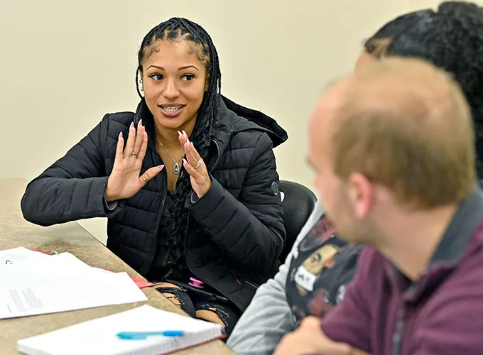 student gesturing while talking with peers