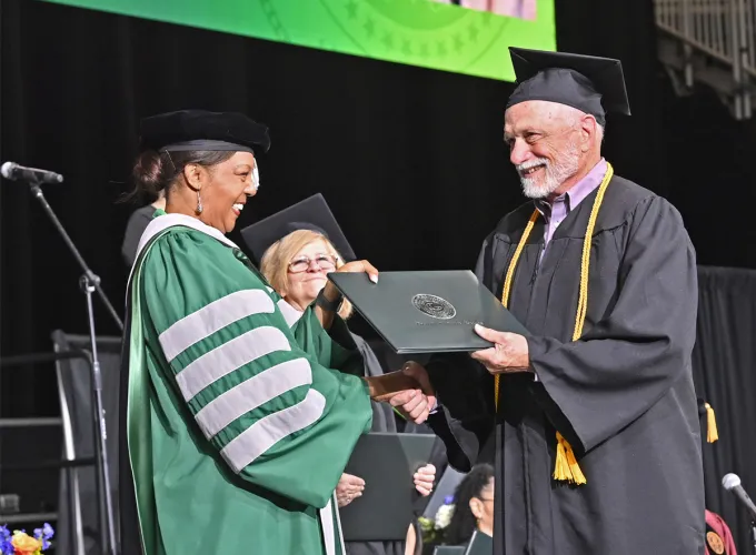 Older graduate receiving diploma from GGC president