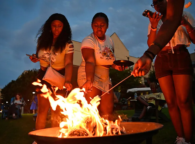 students roasting marshmallows at a bonfire