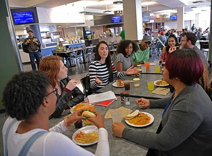 GGC students talking and eating at a long table in the Dining Hall