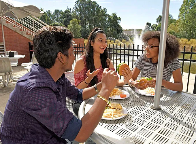 GGC students talking and eating at a patio table in the Dining Hall