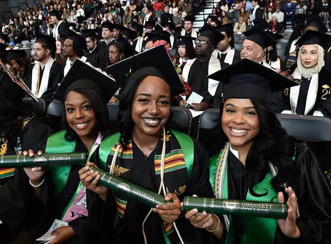 seated grads holding diplomas