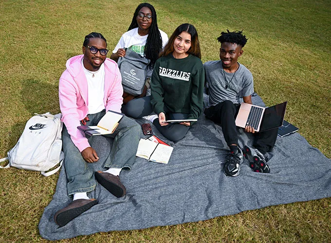Student residents study outdoors seated on blanket