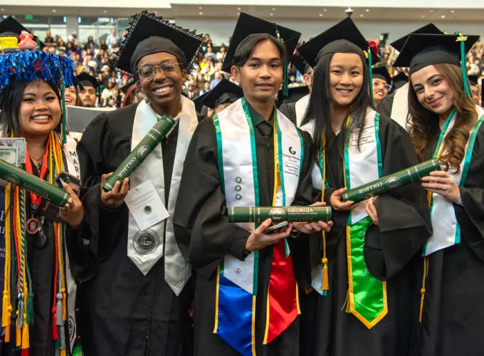 Five students smile at their graduation ceremony
