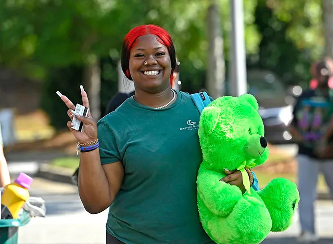 Student resident gesturing a peace sign on move in day with bright green bear