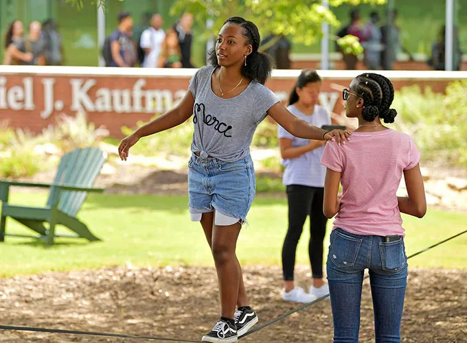Student balancing on a tightrope during an outdoor event