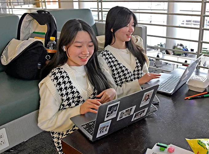GGC students (twins) studying on their laptops in the library