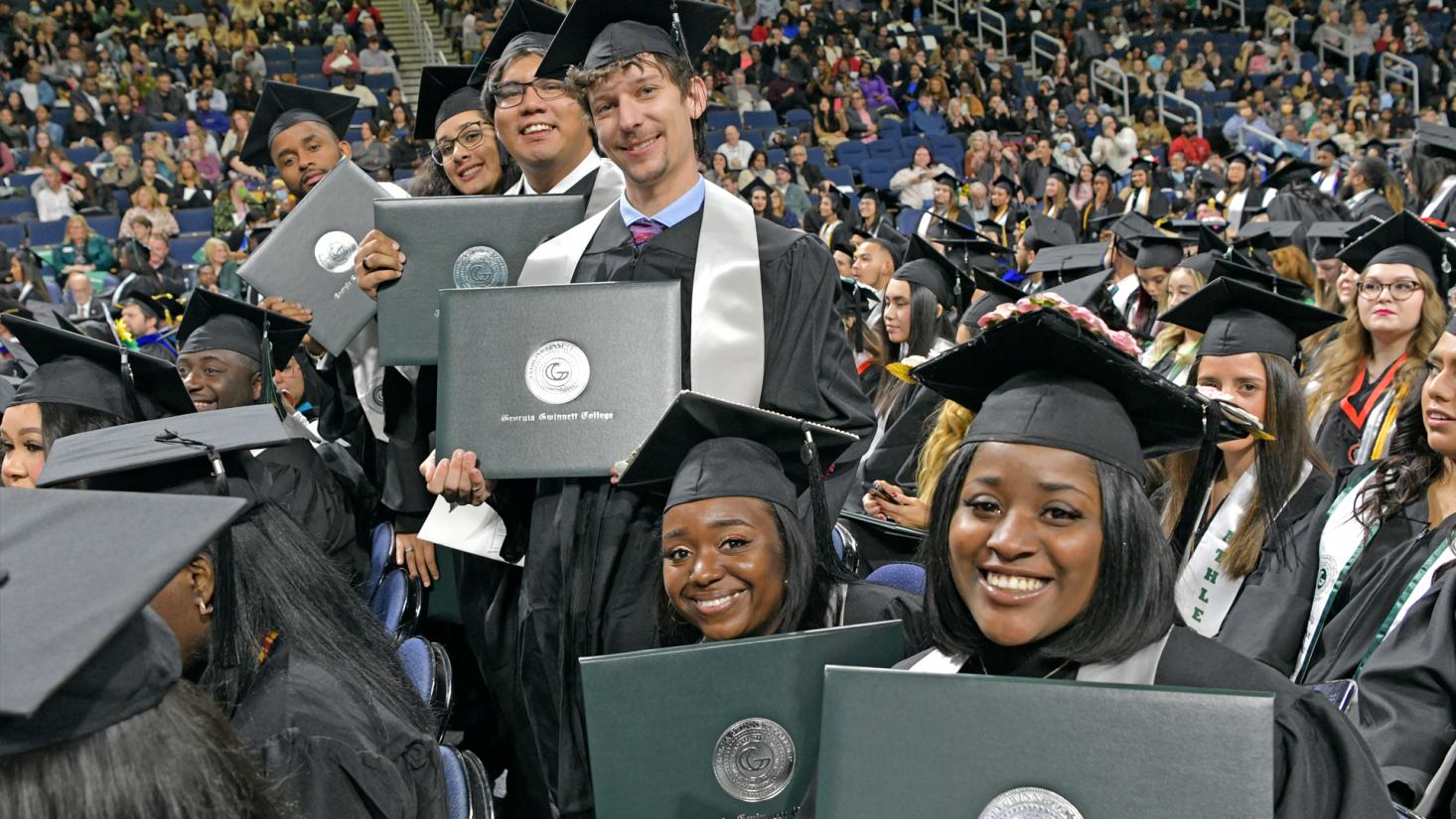 graduates holding their diplomas