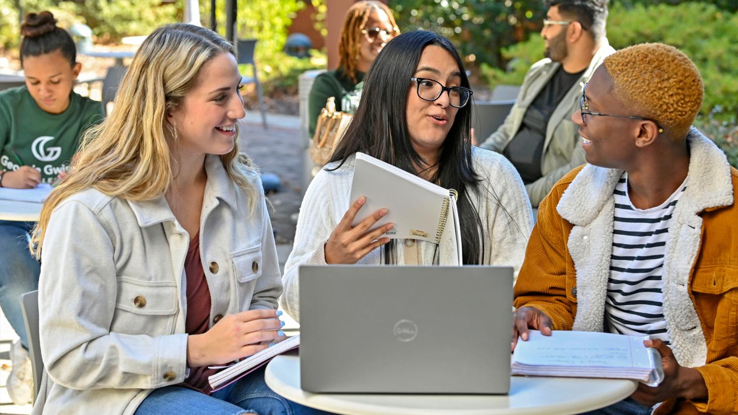 male and female students sitting at patio tables