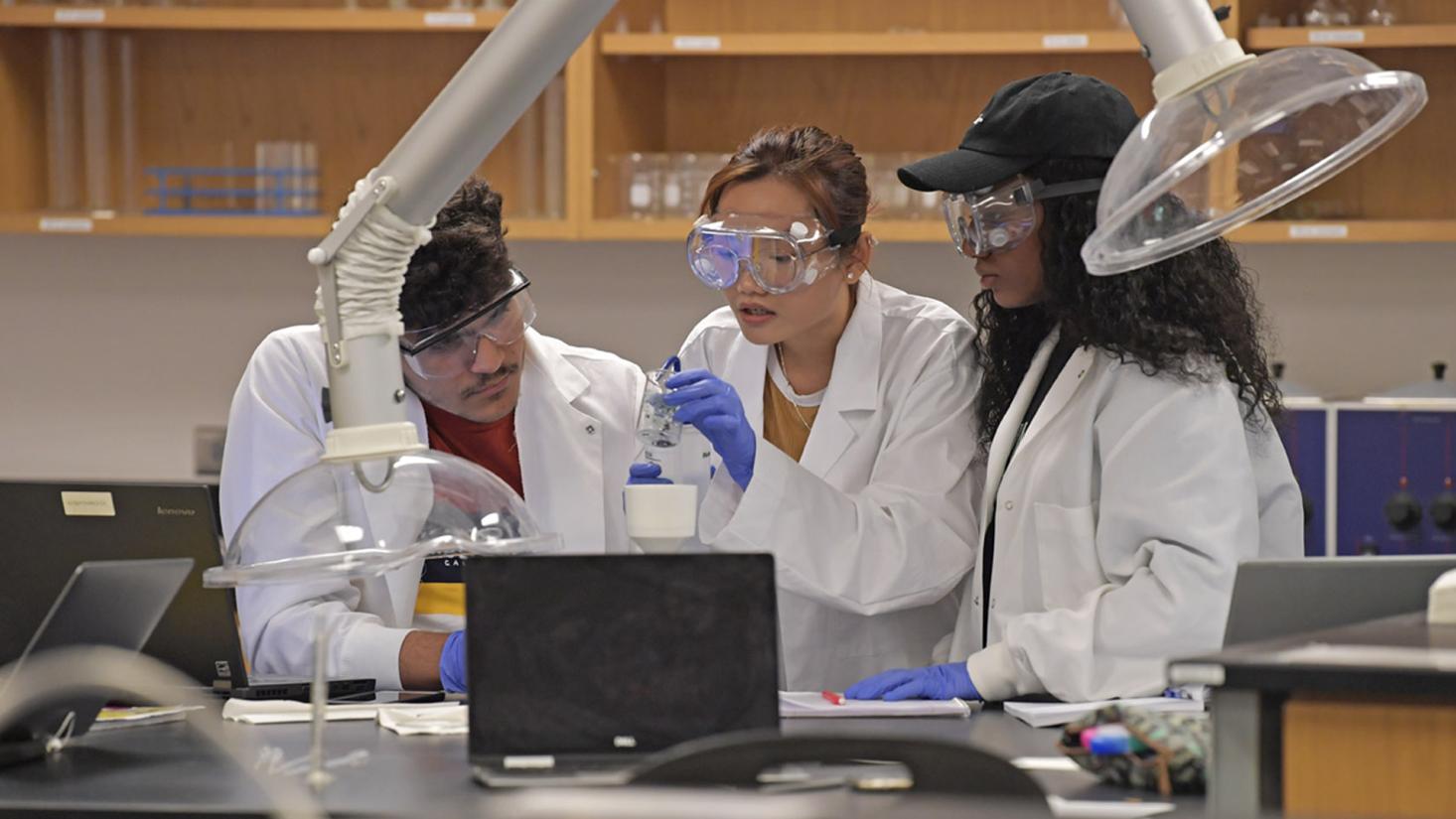 Three students conducting chemistry experiment