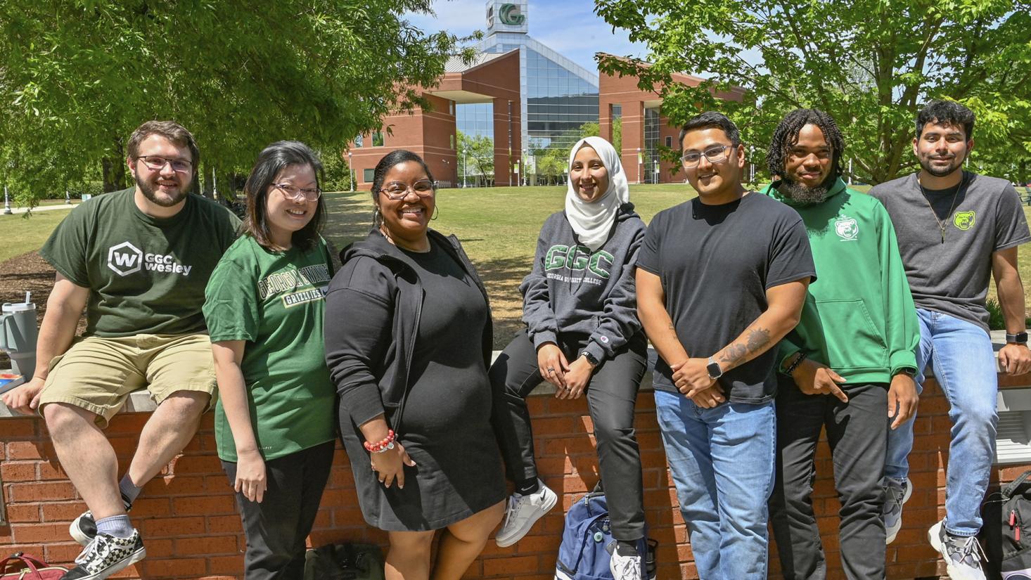 Diverse group of students sitting on a wall outside