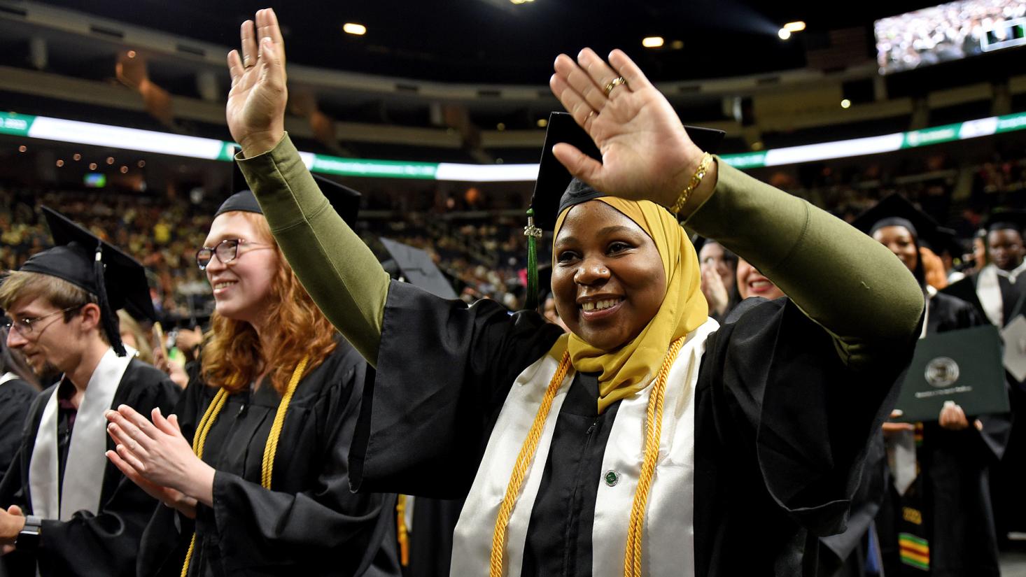 Woman waving arms at graduation ceremony