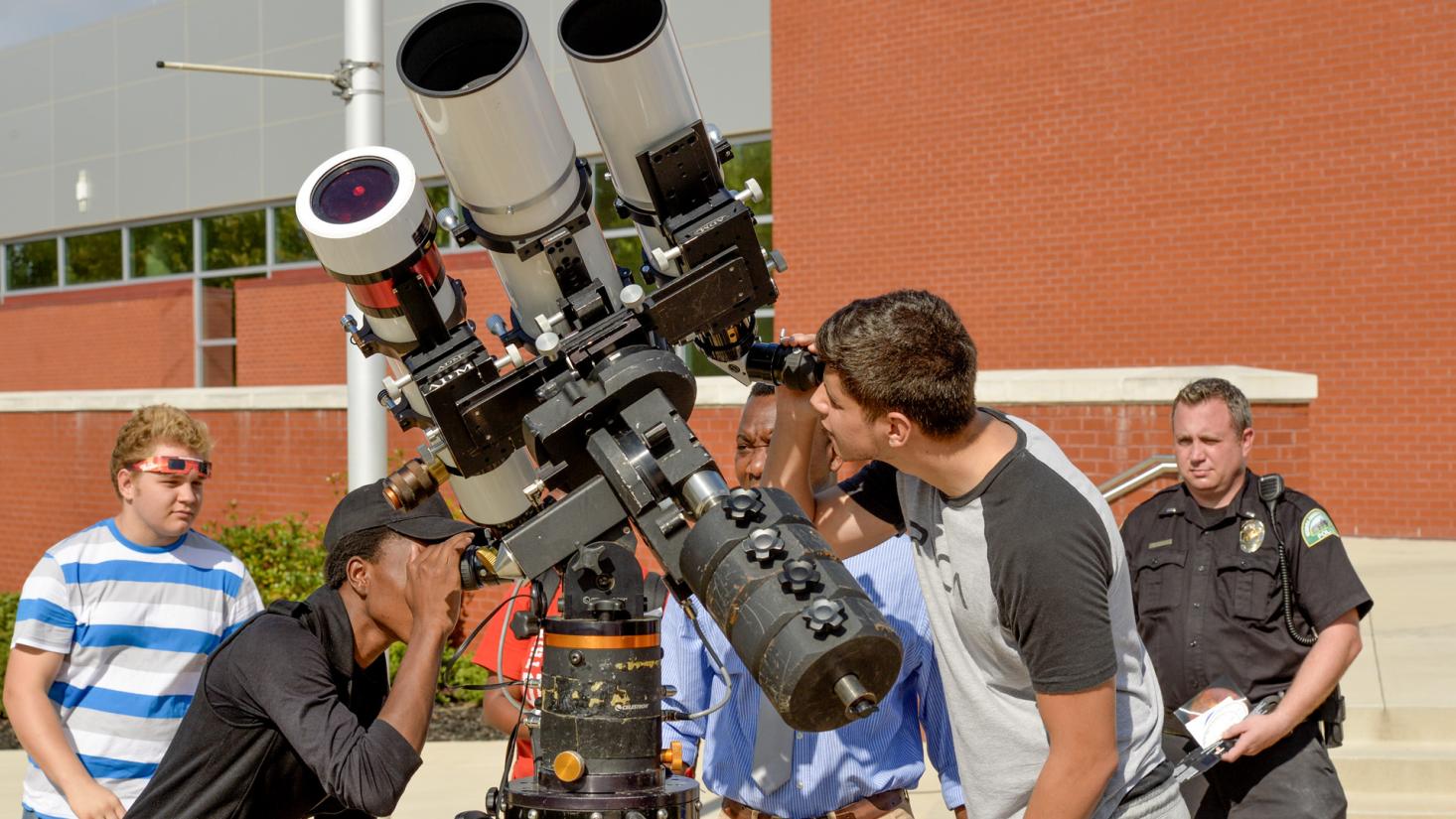 Male students looking through a telescope