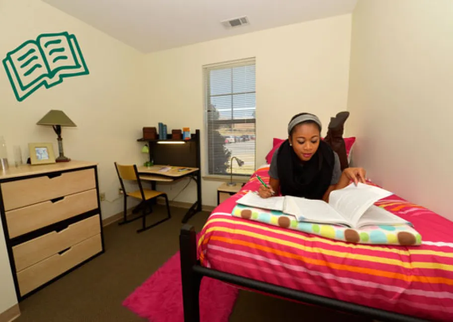 Grizzly resident studying on bed in private room of student housing