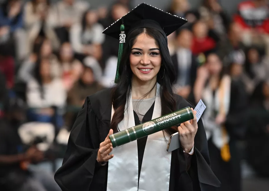 Female graduate holds her diploma.