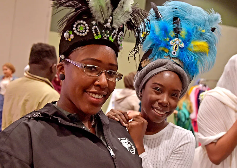 2 students wearing traditional head pieces during international event