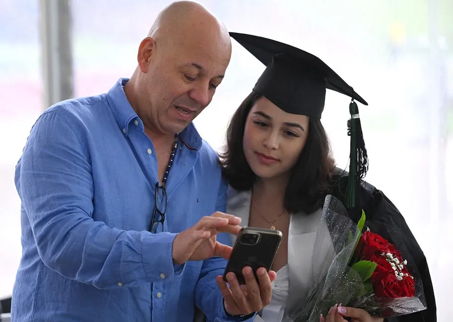 Parent and GGC graduate looking at cell phone