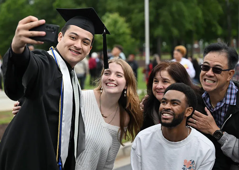 2025 spring graduate taking a selfie with family