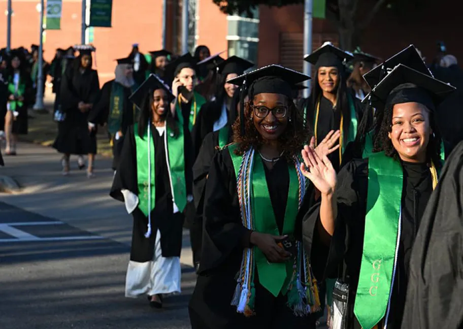 graduates lined up, walking across campus to enter the Convention Center