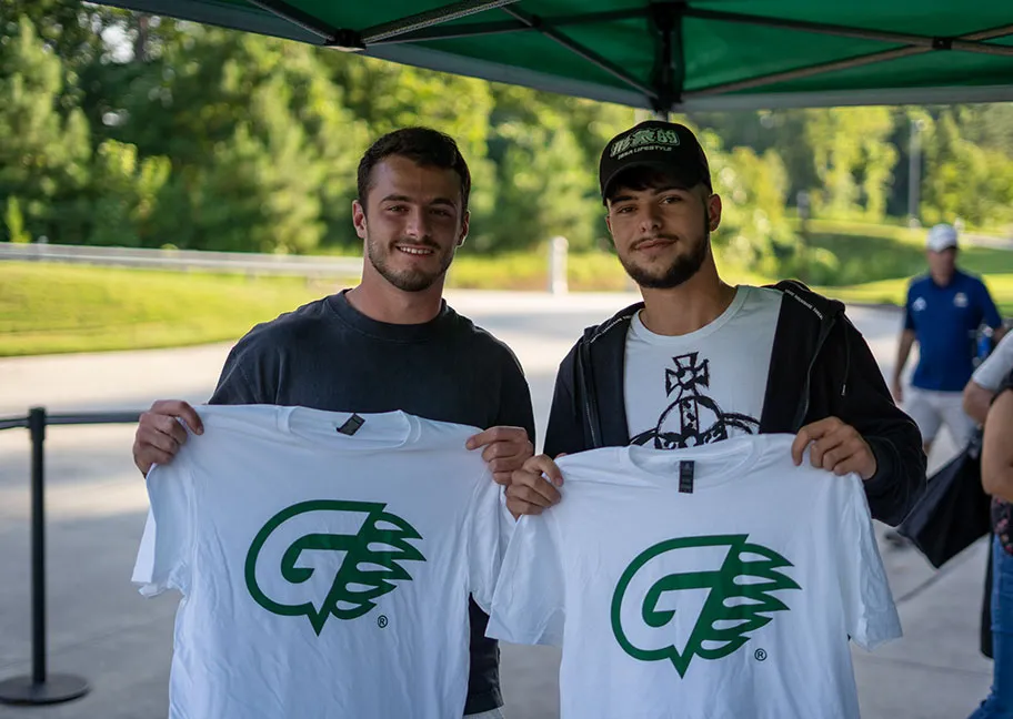 GGC student athletes holding up giveaway t-shirts with GGC Athletics logo