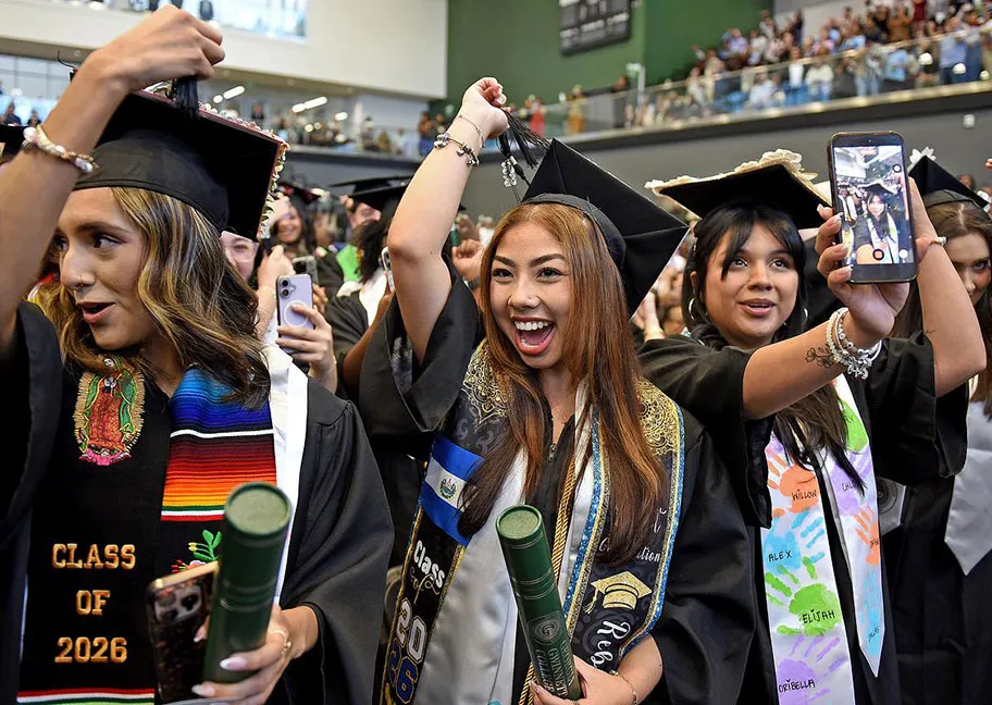 Three graduating seniors turning their tassels during commencement