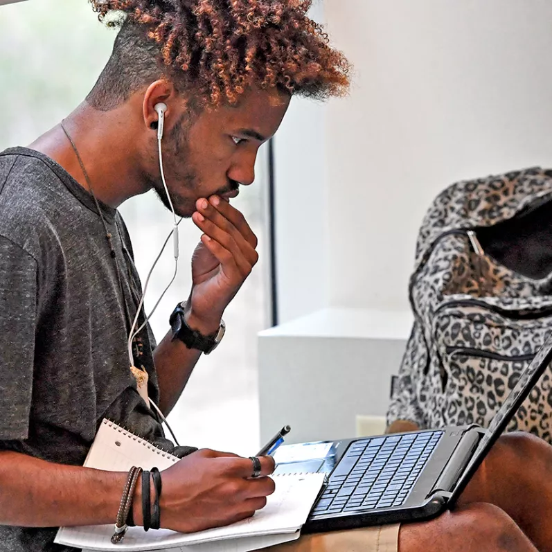 Student studying with notebook and laptop
