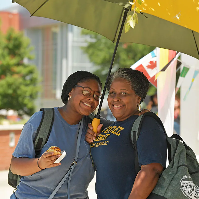 students at International Hot Dog event shaded under an umbrella