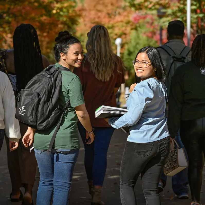 Two students look over their shoulder as they walk