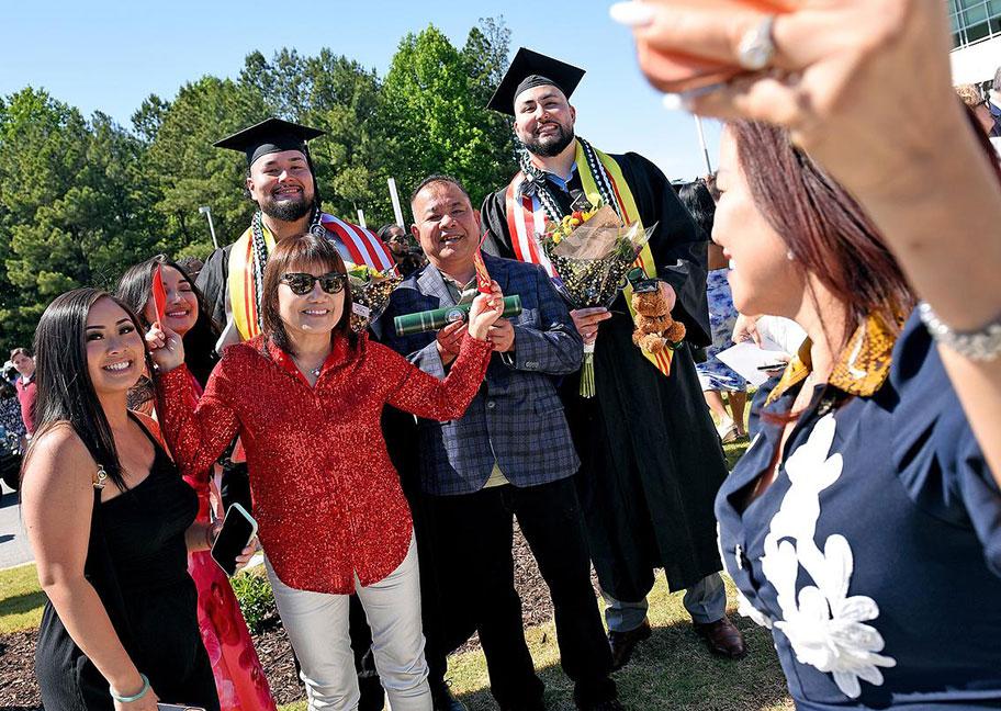 Family posing with their two grads outside commenement