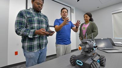 Professor observing students work with a remote-controlled car