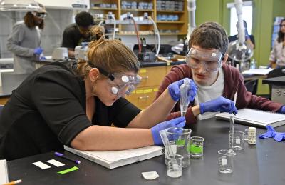Two students in biology lab looking at test tube