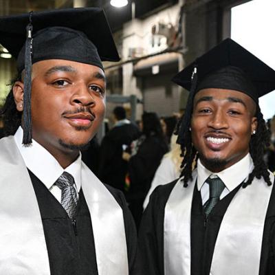 Two GGC grads looking sharp in suits, ties, caps, gowns